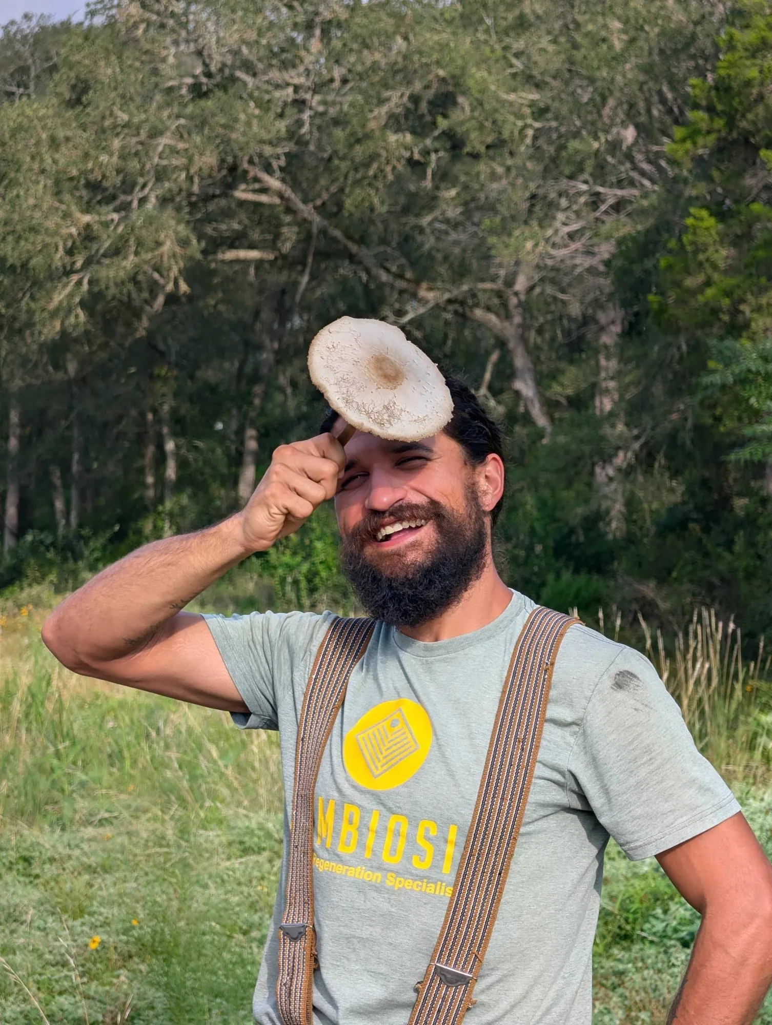 Sam the Fungi holding a foraged wild mushroom in a Central Texas meadow